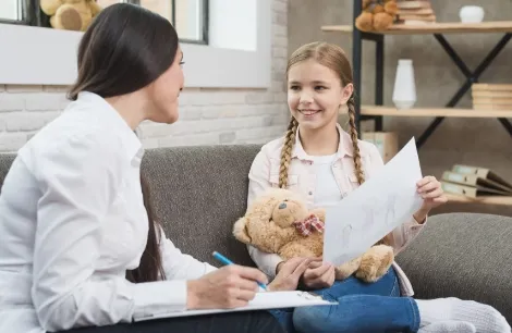 Psychologist taking notes during a child therapy session at PCBH